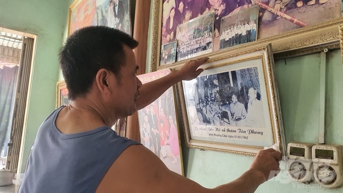 Người con trai cả của cụ Mùi bên bức ảnh quý của gia đình lưu giữ hình ảnh Bác Hồ về thăm quê hương. Ảnh: Kiên Trung.
