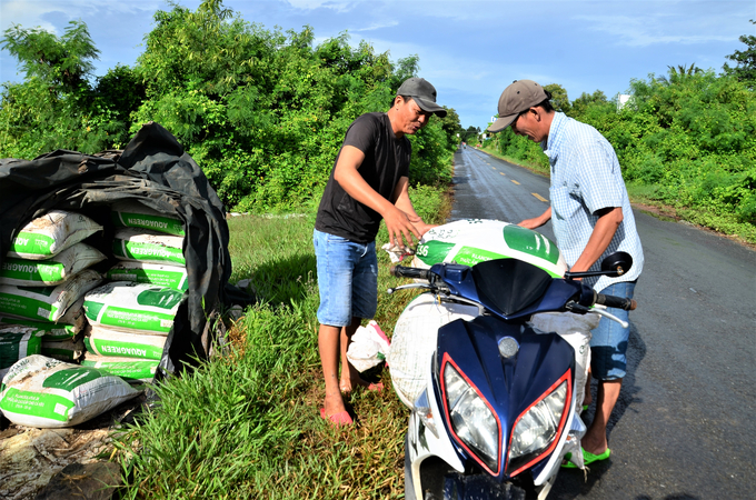 Mr. Nguyen Thanh Sang and Mr. Nguyen Thanh Mong from Vinh Thinh commune loading bags of pink salt onto a vehicle for retail. Photo: Duong Dinh Tuong.