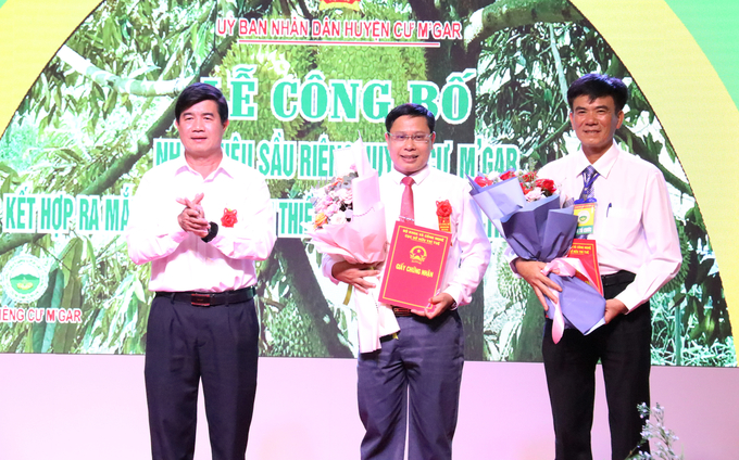 Lãnh đạo UBND huyện Cư M'gar nhận giấy chứng nhận nhãn hiệu 'Sầu riêng Cư M'gar'. Ảnh: Quang Yên.