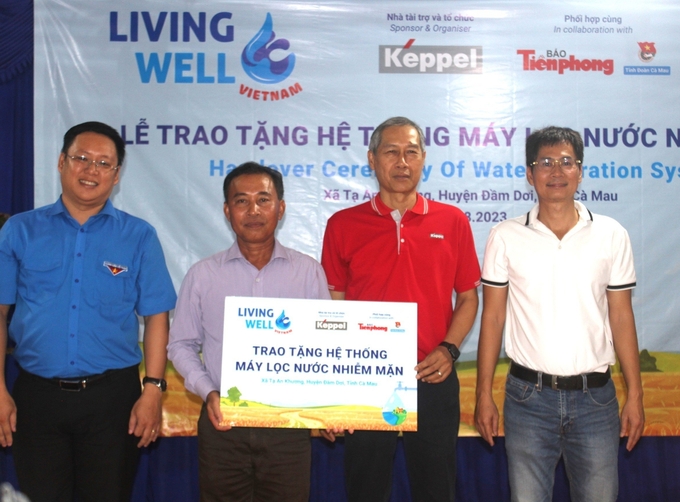 Ông Trịnh Văn Phến - Chủ tịch UBND xã Tạ An Khương (thứ 2 từ trái sang) nhận bản tượng trưng công trình hệ thống máy lọc nước nhiễm mặn. Ảnh: TL.