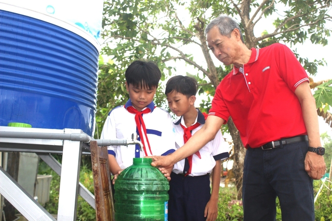 Các em học sinh Trường THCS Tạ An Khương tham gia tìm hiểu hệ thống máy lọc nước nhiễm mặn thuộc dự án Living Well. Ảnh: TL.