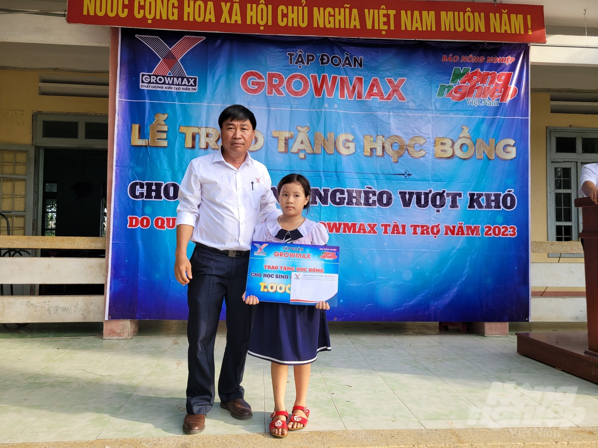 Ông Nguyễn Văn Đại, Giám đốc Khu vực miền Trung 2 (Công ty TNHH Thức ăn thủy sản GrowMax) trao học bổng cho em Nguyễn Ngọc Hân, lớp 3C, Trường Tiểu học Hòa An số 1. Ảnh: PC.