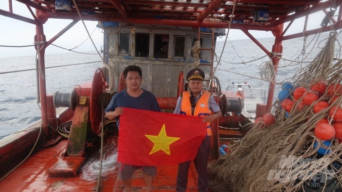 Tổ tuần tra số 7 (Kiểm ngư Vùng V) tặng cờ Tổ quốc cho ngư dân bám biển. Ảnh: Kiên Trung.