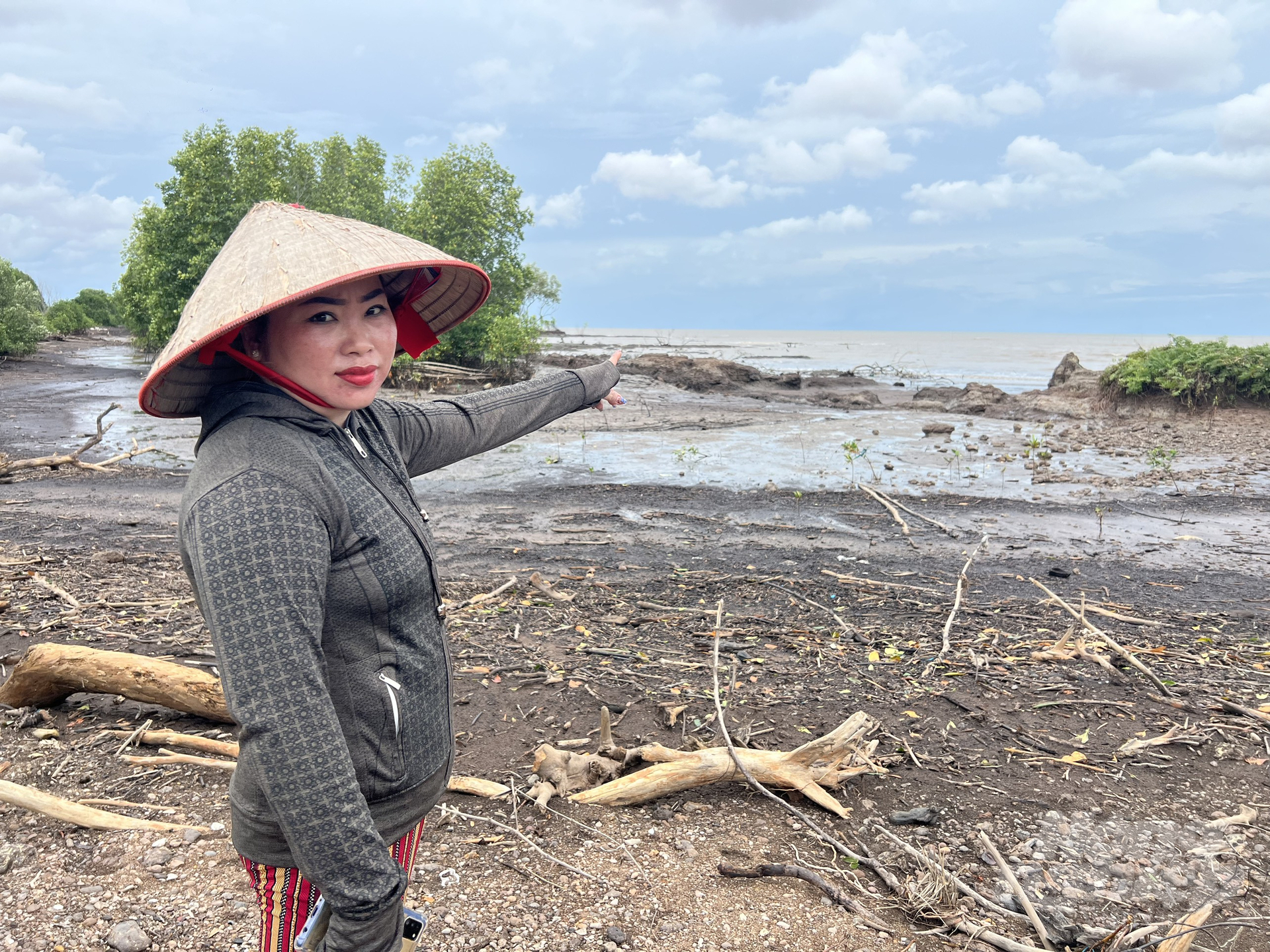 Ms. Yen pointing towards her family's shrimp farming ponds that were washed away by the waves. Photo: Trong Linh.