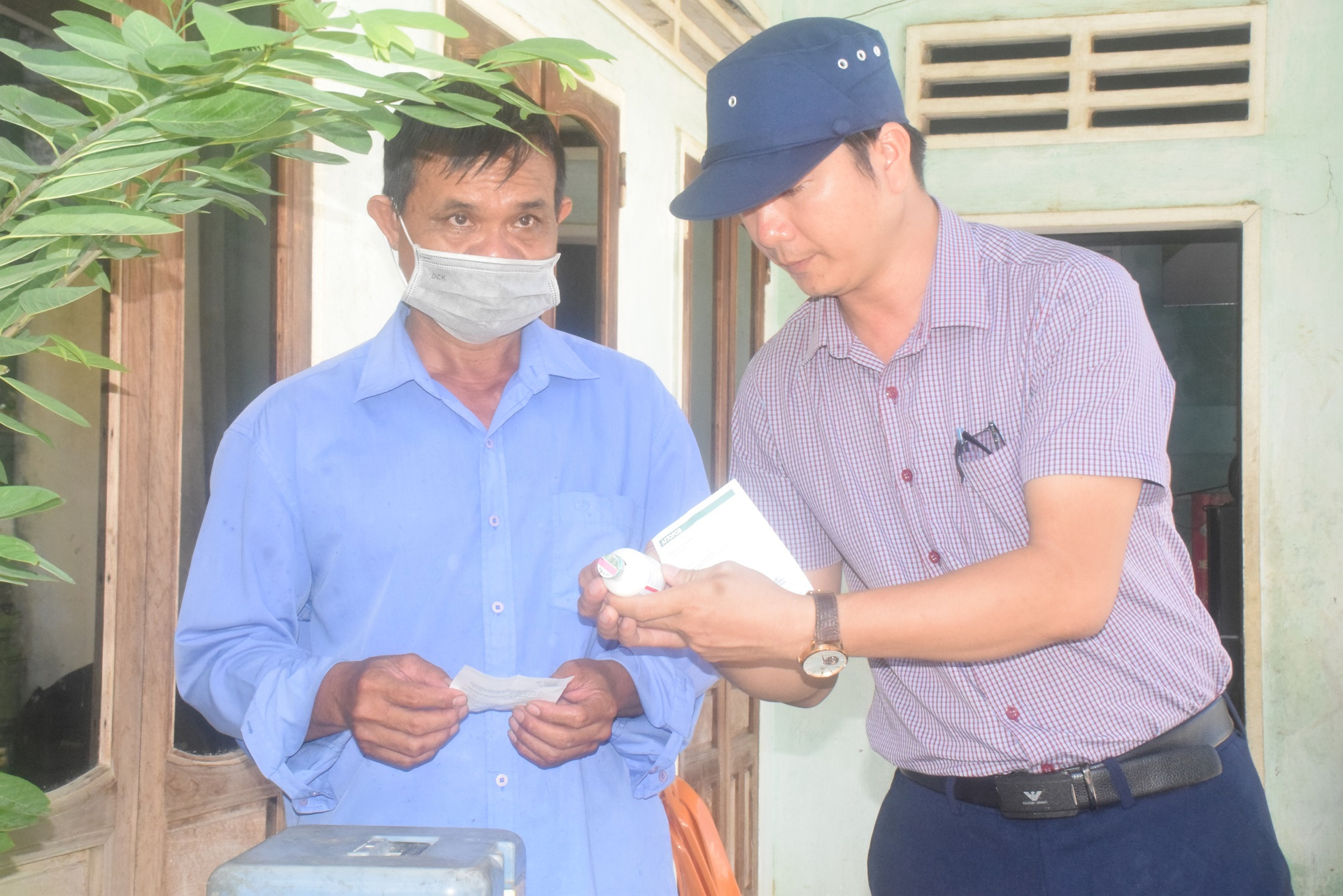 Anh Huỳnh Văn Thạnh (bên phải), bác sĩ Trung tâm Dịch vụ nông nghiệp thị xã An Nhơn (Bình Định) dặn dò anh Nguyễn Hữu Độ, cán bộ thú y xã Nhơn Lộc về công tác tiêm phòng. Ảnh: V.Đ.T.