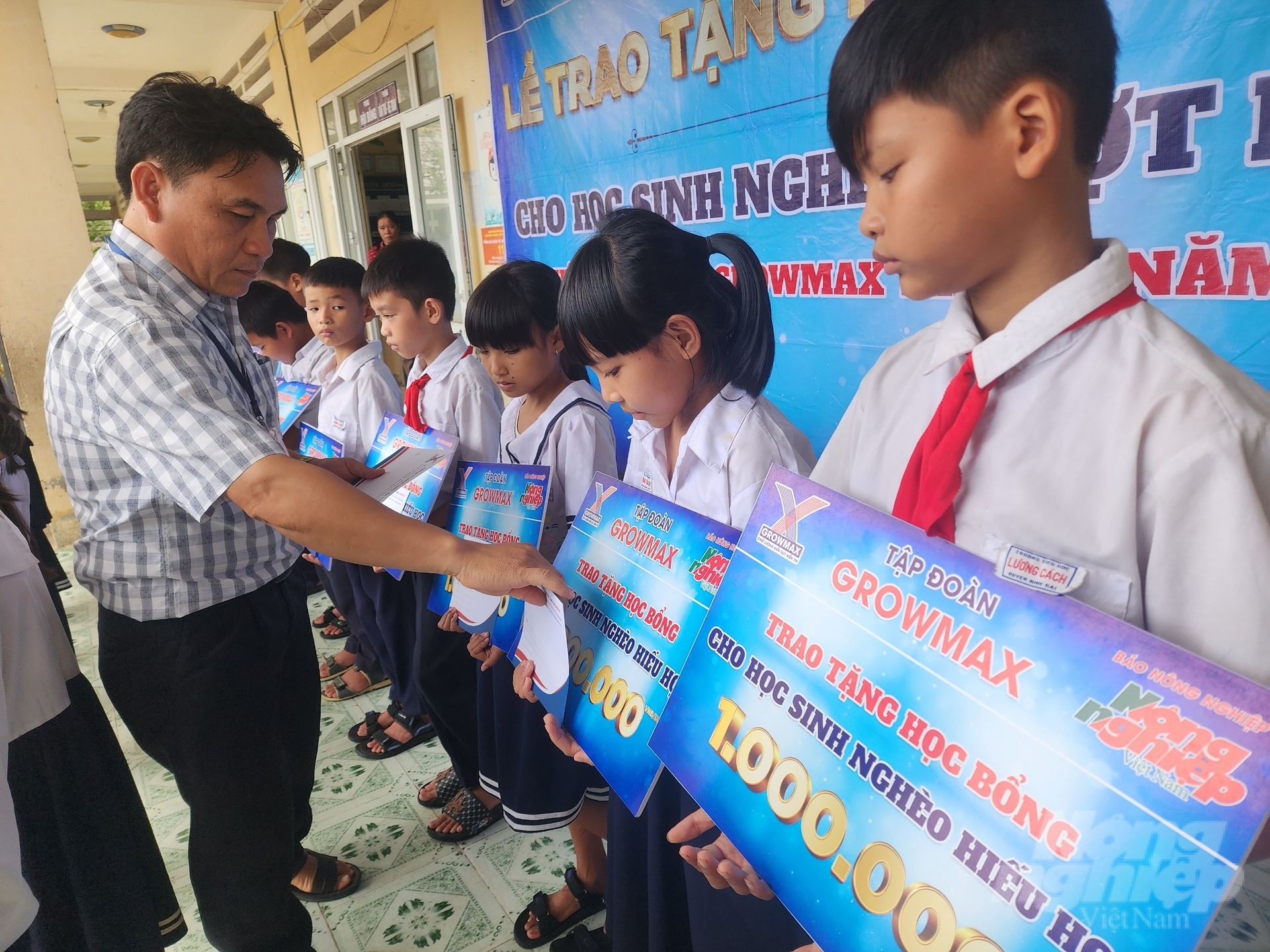 Thầy Đỗ Minh Đức, Hiệu trưởng Trường Tiểu học Lương Cách trao học bổng cho các em học sinh. Ảnh: Phương Chi