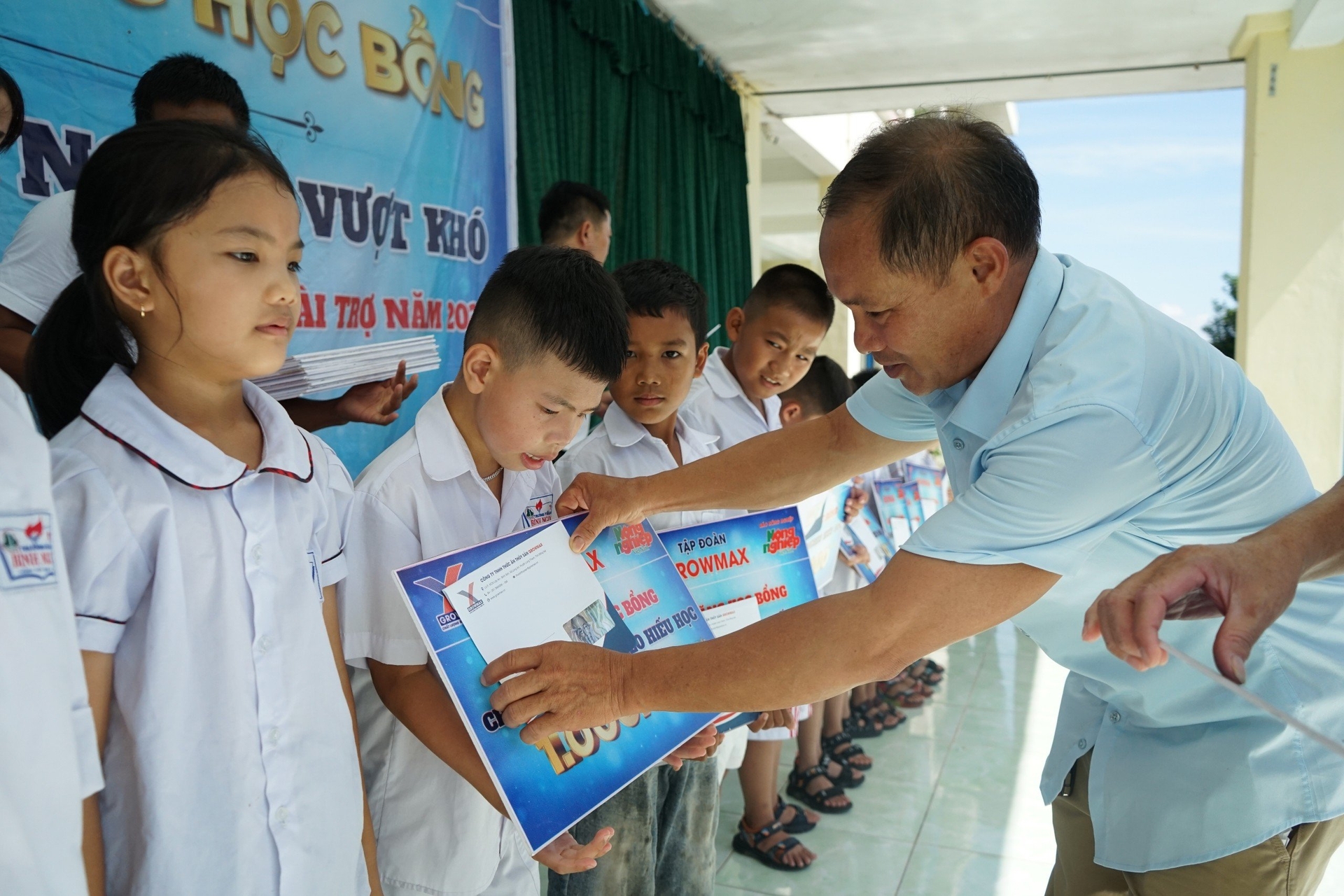 Đại diện Công ty thức ăn thủy sản GrowMax khu vực Móng Cái trao quà cho các em học sinh nghèo vượt khó trường Tiểu học Bình Ngọc.
