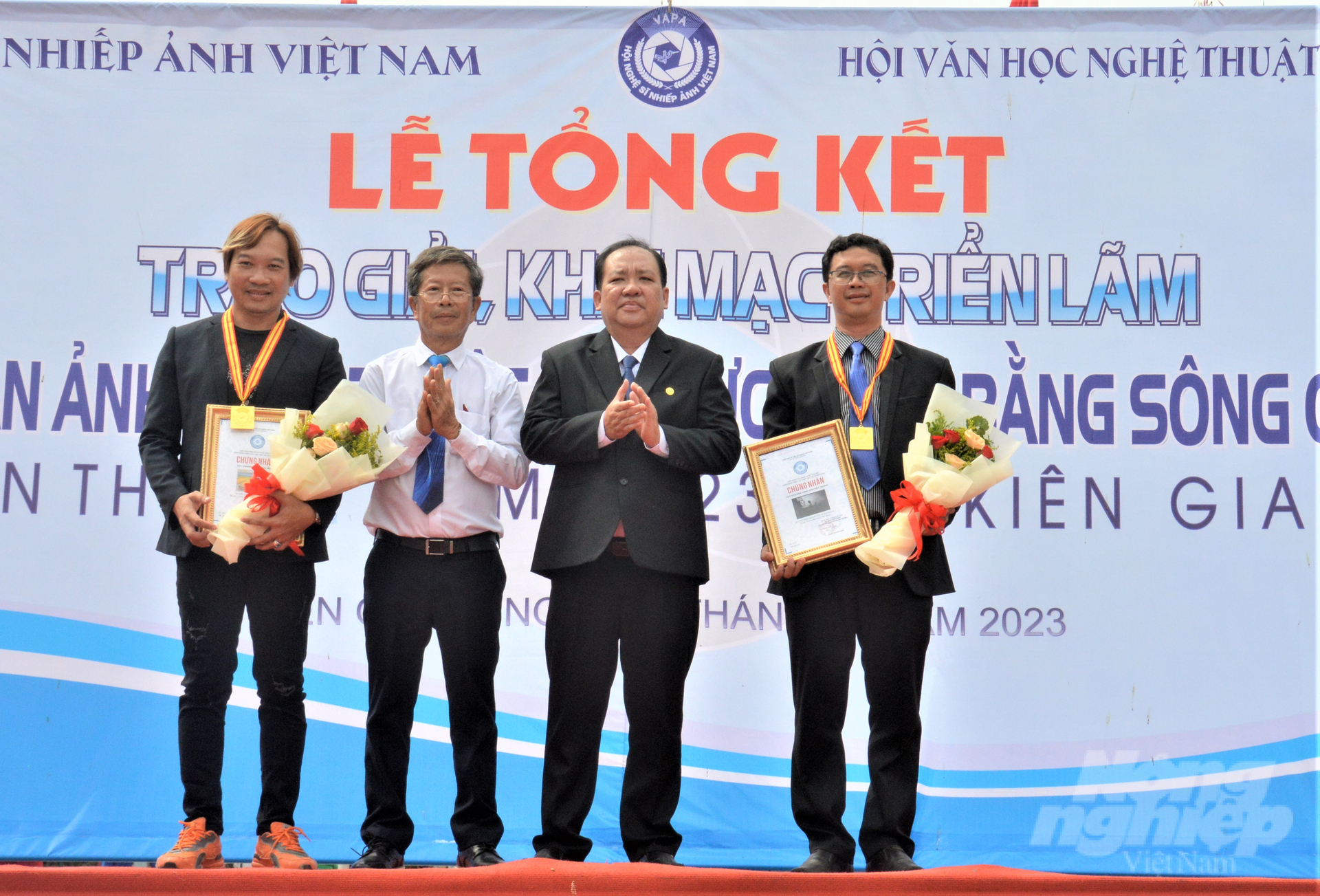 Ban Tổ chức liên hoan ảnh nghệ thuật khu vực ĐBSCL lần thứ 38 năm 2023 tại tỉnh Kiên Giang trao Huy chương vàng cho tác giả Lý Anh Lam (bìa trái) với tác phẩm 'Hạt vàng gieo những niềm vui' và tác giả Trương Minh Nhựt  (bìa phải) với tác phẩm tác phẩm 'Nghiện game âm thầm tàn phá tương lai'. Ảnh: Trung Chánh. 