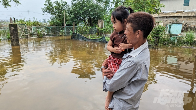 Cha con ông Lộc nhìn xa xăm, mong nước lụt nhanh rút để cuộc sống trở lại bình thường.