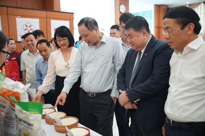 Mr. Nguyen Nhu Tiep, Director of the Department of Quality, Processing and Market Development (blue shirt standing in the middle), and delegates visited the booth displaying and introducing agricultural products at the Seminar. Photo: Linh Linh.