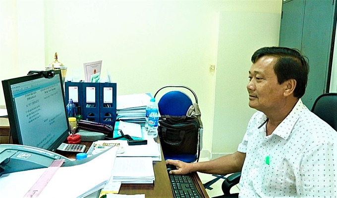 Ông Trang Tấn Tài, Giám đốc Trung tâm Quản lý công trình thủy lợi tỉnh Long An bên đống văn bản, giấy tờ hành chính như chiếc 'vòng kim cô' trói buộc khiến hoạt động của đơn vị gặp nhiều khó khăn. Ảnh: Hồ Thảo.