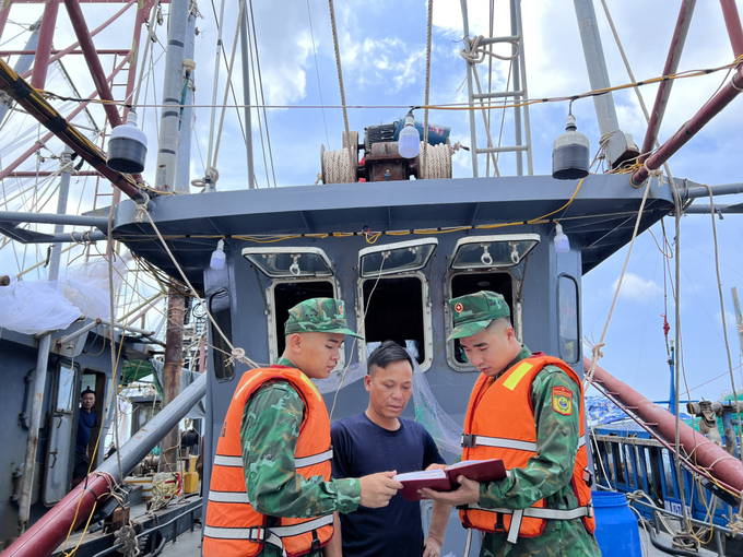 Cán bộ chiến sĩ Đồn biên phòng Trà Cổ (TP Móng Cái) tuyên truyền cho ngư dân các quy định về khai thác thủy sản. Ảnh: ĐVCC.