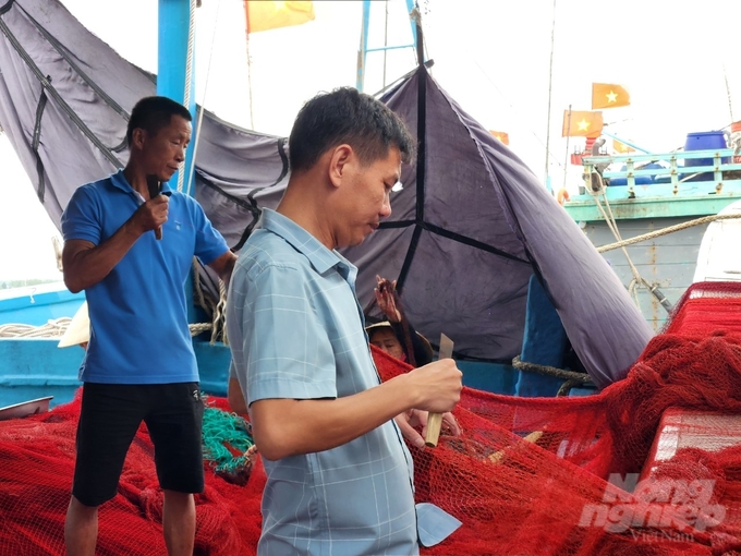 Ngư dân Nguyễn Hữu Hải cùng người lao động tu sửa lại ngư cụ, chuẩn bị vươn khơi. Ảnh: Tâm Phùng.