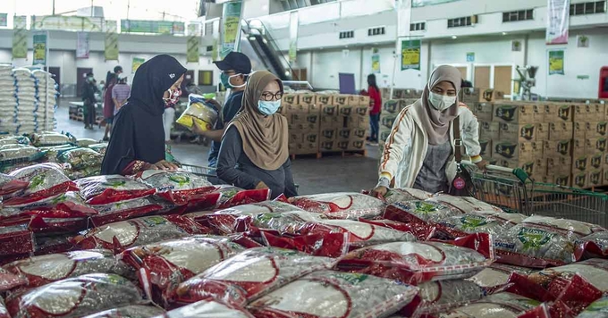 Người dân mua gạo giá rẻ và các hàng tạp hóa khác tại một nhà kho ở Surabaya, Đông Java, Indonesia. Ảnh: AFP.