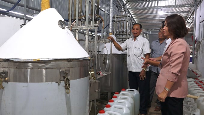 Khoan (white shirt) next to the boiler system used to extract agarwood essential oil. Photo: Tran Trung.