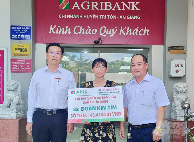 Đại diện gia đình khách hàng bà Đoàn Kim Tím nhận số tiền bảo hiểm Agribank với số tiền 146 triệu đồng. Ảnh: Lê Hoàng Vũ.