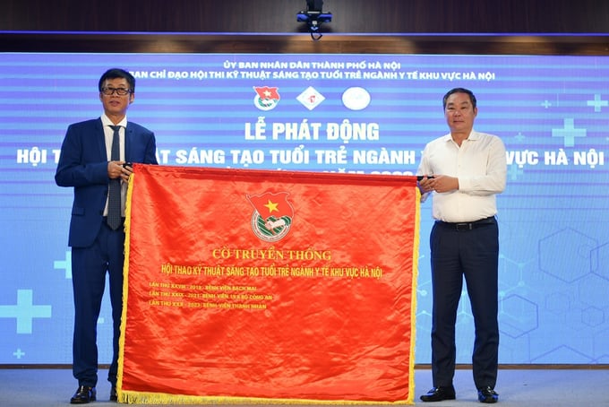 Phó Chủ tịch Thường trực UBND TP Lê Hồng Sơn (bên phải) trao cờ truyền thống cho PGS, TS Đào Quang Minh, Giám đốc Bệnh viện Thanh Nhàn - đơn vị đăng cai Hội thi năm nay. 
