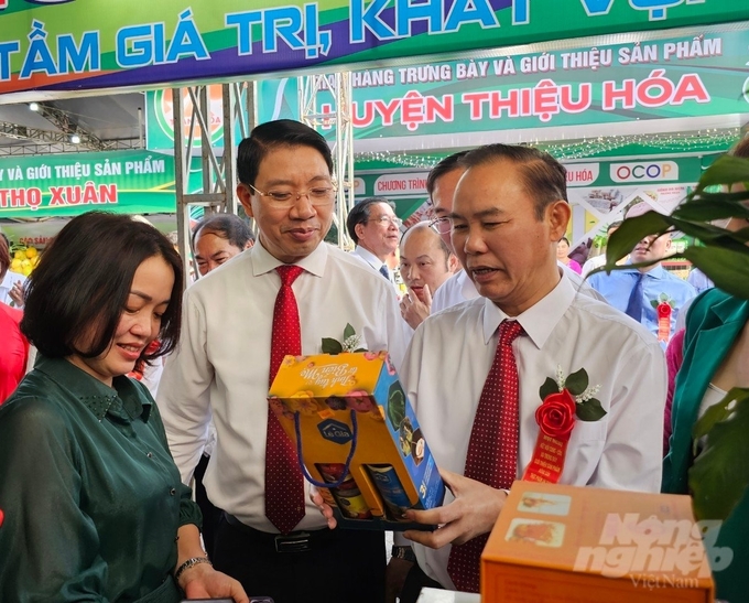 Deputy Minister Phung Duc Tien (right) visits agricultural booths at the exhibition.