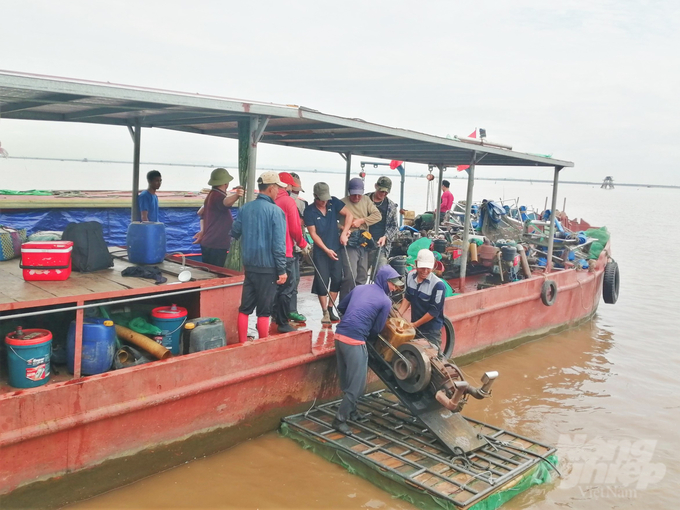 Các thành viên trong đội đưa máy sục xuống bè xốp nhỏ, di chuyển ra khu vực khai thác ngao. Ảnh: Trung Quân.