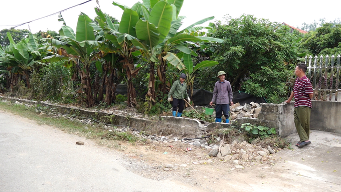 Ông Lê Mai Quế (đứng giữa) cùng người thân tháo dỡ hàng rào để mở rộng đường. Ảnh: Quang Linh.