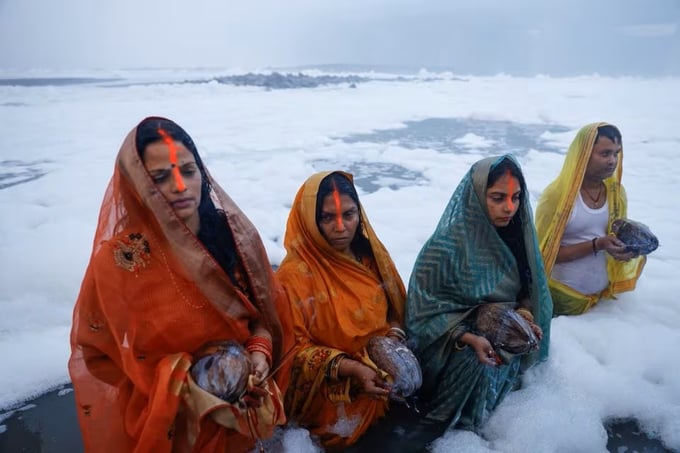 Các tín đồ đạo Hindu đứng giữa làn bọt trắng ô nhiễm trên sông Yamuna trong lễ hội Chhath Puja ở New Delhi, Ấn Độ, hôm 20/11. Ảnh: Reuters.