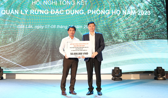 Ông Trần Quang Bảo, Cục trưởng Cục Lâm nghiệp trao phần quà hỗ trợ cho gia đình ông Nguyễn Kim Anh. Ảnh: Quang Yên.