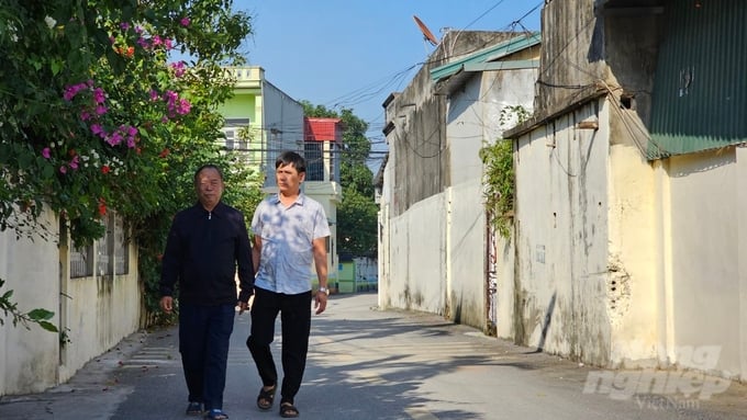 Ông Giới (áo đen, bên trái) đi trên con đường thôn Hiền Đông do chính gia đình ông bỏ tiền xây dựng. Ảnh: Quốc Toản.