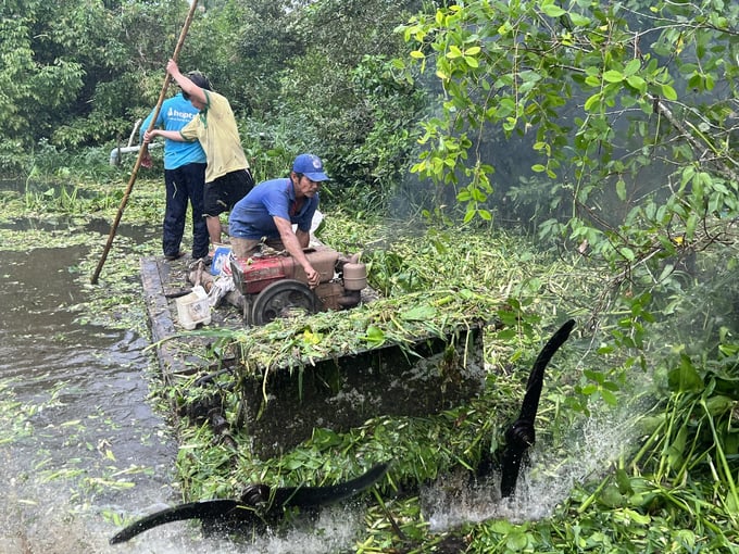 Người dân ấp Thanh Trung, xã Hưng Khánh Trung B, huyện Chợ Lách chặt lục bình khơi thông dòng chảy, phát huy hiệu quả của hệ thống thủy lợi khép kín. Ảnh: Kiều Nhi.