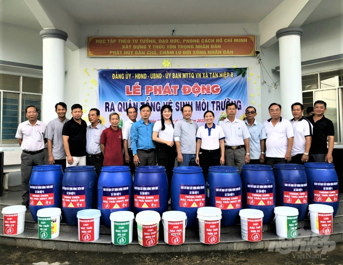 Lãnh đạo UBND xã Tân Hiệp B, cùng các đoàn thể hỗ trợ người dân dụng cụ phân loại rác, thùng ủ rác hữu cơ để phục vụ sản xuất, nâng cao thu nhập. Ảnh: Trung Chánh.
