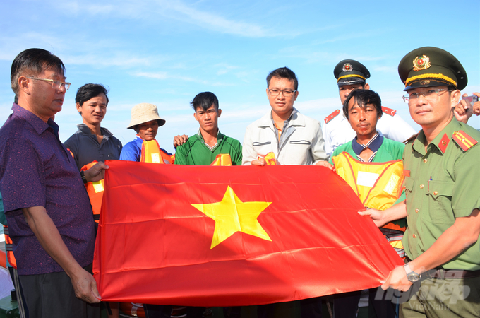 Lãnh đạo Sở NN-PTNT, thường trực Ban chỉ đạo chống khai thác IUU tỉnh Kiên Giang cùng các ngành chức năng tặng cờ, thư kêu gọi của Tỉnh ủy Kiên Giang về chống khai thác IUU cho ngư dân. Ảnh: Trung Chánh.
