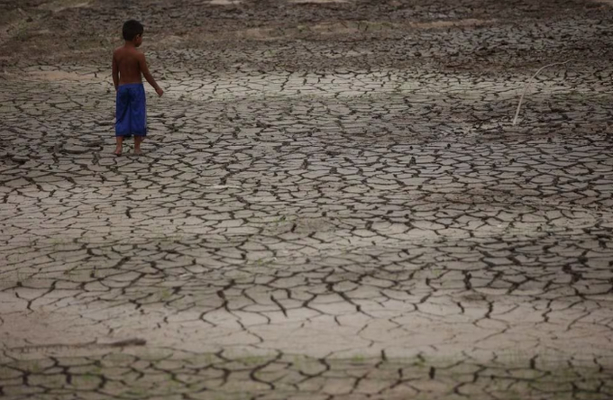A boy walks on a dry area of the Igarape do Taruma stream which flows into the Rio Negro river, as the water level at a major river port in Brazil's Amazon rainforest hit its lowest point in at least 121 years on Monday, in Manaus, Brazil October 16, 2023. REUTERS/Bruno Kelly/File Photo Acquire Licensing Rights