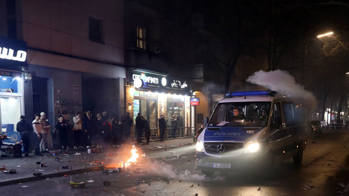 Xe cảnh sát đi qua nơi nhiều đối tượng bắn pháo hoa bừa bãi trên phố Sonnenallee ở quận Neukolln của Berlin, Đức, hôm 1/1. Ảnh: RT.