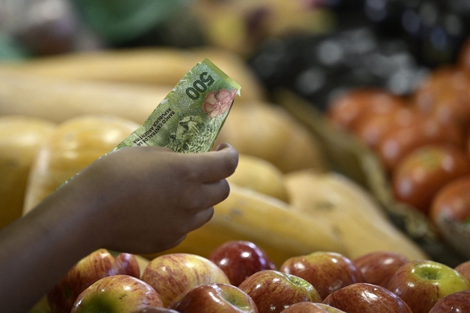 Một người phụ nữ thanh toán bằng tiền mặt tại một quầy bán lẻ ở Chợ Trung tâm Buenos Aires hồi tháng 2/2023. Ảnh: AFP.