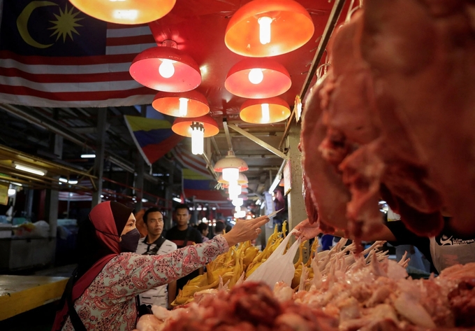 Một người phụ nữ mua thịt gà tại một khu chợ ở Kuala Lumpur, Malaysia. Ảnh: Reuters.