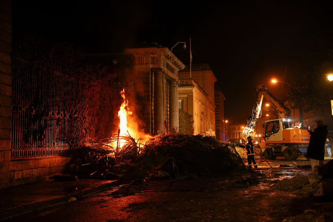 Một lính cứu hỏa đang cố gắng dập lửa sau khi nông dân đốt rơm và phân trước cửa tòa nhà hành chính chính phủ ở Agen, miền nam Pháp, hôm 24/1. Ảnh: Reuters.