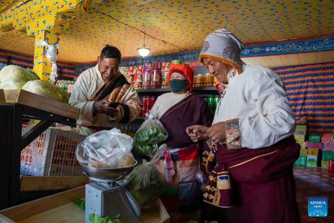Quản lý cửa hàng Sherab Gyatso (ngoài cùng bên ​​phải) đang cân rau cho một người dân trong làng tại một cửa hàng bán hàng trực tiếp ở làng Beiga, huyện Thân Trát. Ảnh: Tân Hoa Xã. 