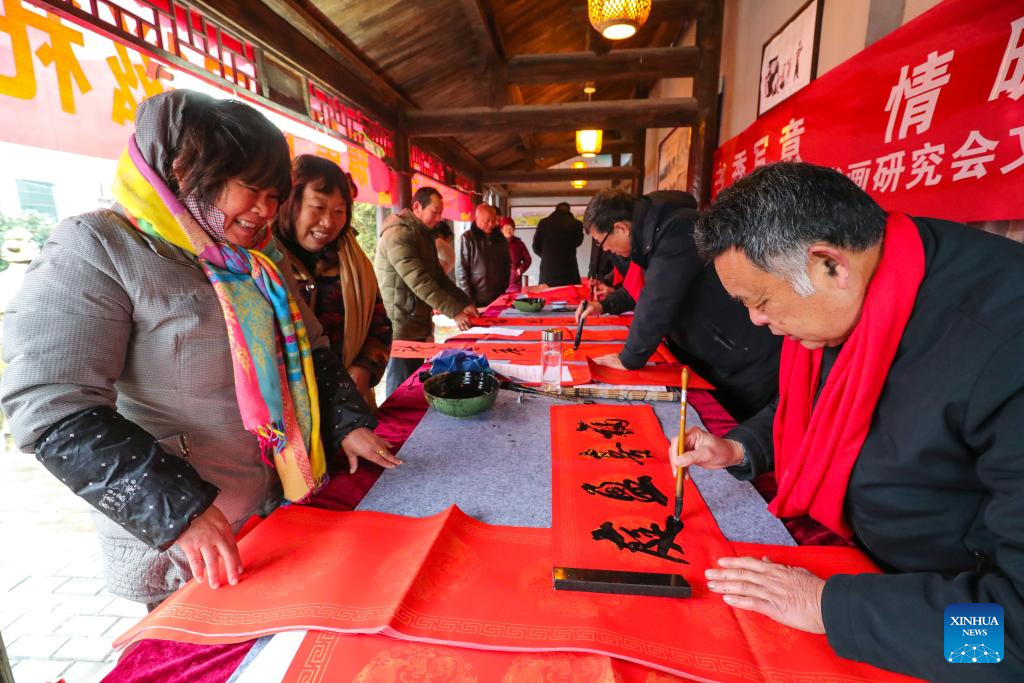 Những người yêu thích thư pháp Trung Quốc viết câu đối Tết cho người dân địa phương ở huyện Quảng Sơn của Tín Dương, tỉnh Hà Nam, miền trung Trung Quốc. Ảnh: Tân Hoa Xã. 