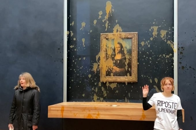 Hai người biểu tình hất súp bí đỏ vào bức tranh Mona Lisa nổi tiếng ở bảo tàng Louvre, Paris hôm 28/1. Ảnh: AFP.