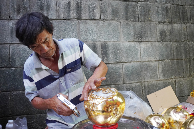 Trái dừa đã được phủ vàng miếng 24K, người thợ tiếp tục trang trí phụ kiện cho dừa. Ảnh: Nguyễn Thủy.