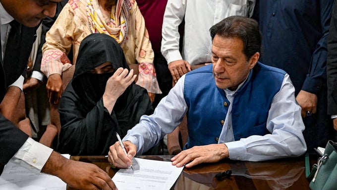 Cựu Thủ tướng Pakistan Imran Khan cùng với vợ Bushra Bibi ký giấy bảo lãnh để được tại ngoại, tại Tòa án tối cao, ở Lahore, hồi tháng 7/2023. Ảnh: AFP.