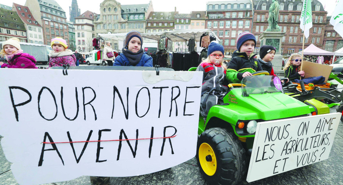 Sons and daughters of French farmers march in Strasbourg, France on Wednesday behind a miniature vehicle and a sign reading 'For our future' as demonstrations about the agriculture sector continue. Photo: FREDERICK FLORIN/AFP