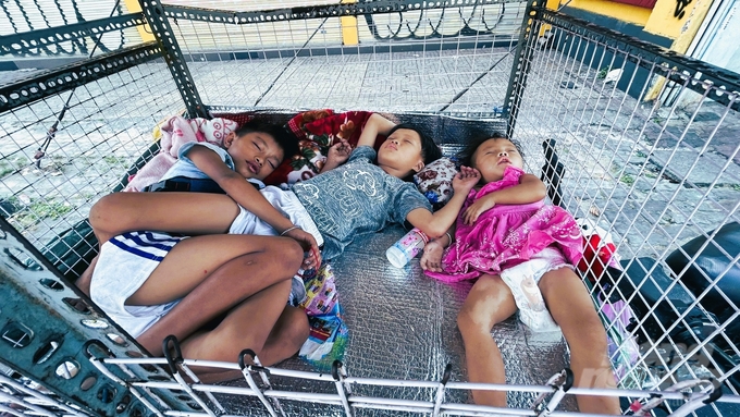 Trong khi nhiều người hối hả về quê đón Tết, thì những em bé cơ nhỡ ngủ ngon lành trong chiếc lồng sắt bên vệ đường.