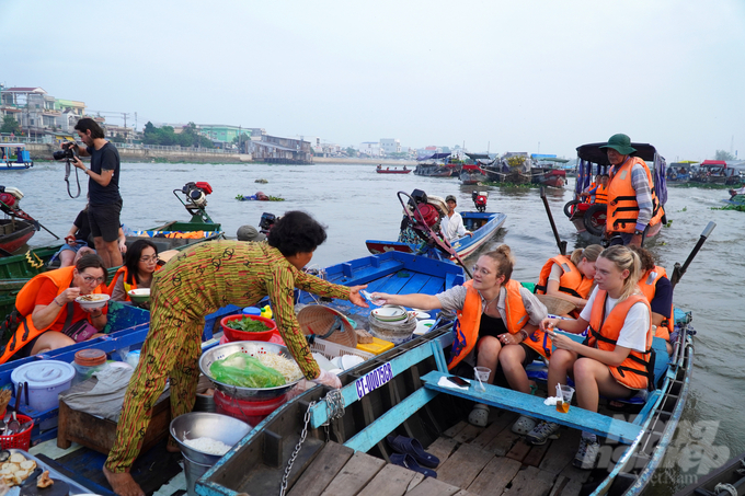 Những du khách Tây cười vui và thư giãn trên thuyền trên dòng sông Hậu, hòa mình vào không gian Tết ấm áp và sôi động của chợ nổi Cái Răng.