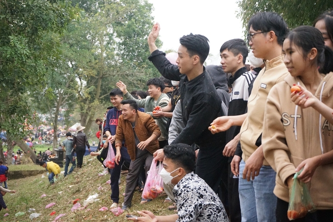 Các tốp thanh niên tay cầm quả, ngồi trên bờ đê chờ ném nhau. Người ném và người bị ném đứng cách xa nhau một đoạn. Người dân cho rằng, người càng bị ném nhiều càng gặp may mắn.