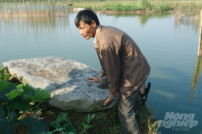 Ông Phạm Văn Tuấn (xóm Chùa) biểu diễn tư thế một chân quỳ gối, tay trái đặt vào vị trí gắn với câu chuyện thầy Tàu giấu kho báu bên trong phiến đá. Ảnh: TL.