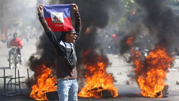 Một người biểu tình giương cờ Haiti yêu cầu Thủ tướng Ariel Henry từ chức ở Port-au-Prince, Haiti, hôm 1/3. Ảnh: AP.