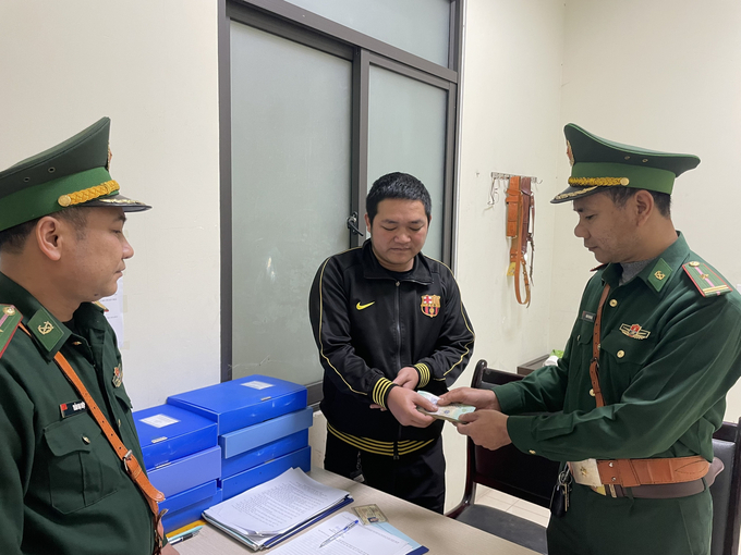 Cán bộ Đồn Biên phòng cửa khẩu quốc tế Cha Lo trao trả lại tài sản cho anh Đinh Thuận. Ảnh: Đ.Trí.