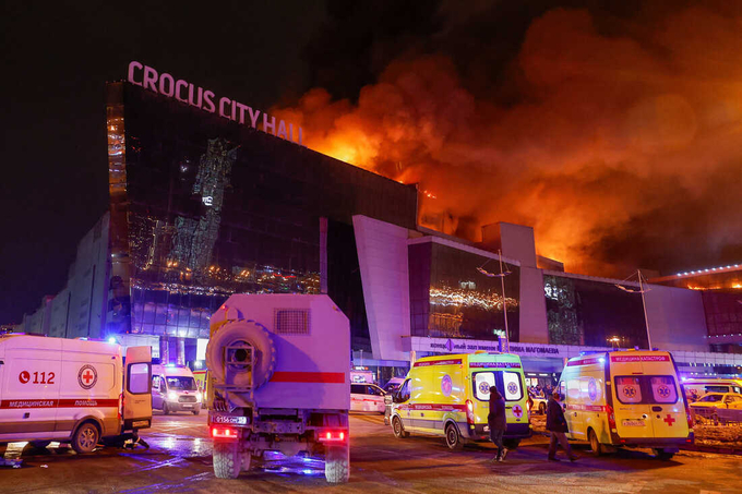 Xe của lực lượng cứu hộ Nga gần trung tâm thương mại Crocus City Hall đang bốc cháy sau vụ tấn công khủng bố ở ngoại ô Moscow tối 22/3. Ảnh: Reuters.
