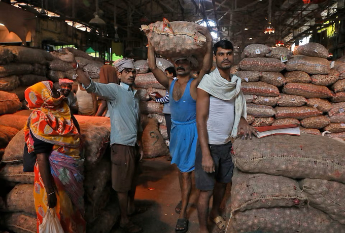 Người lao động bốc dỡ các bao hành tây tại chợ bán buôn ở thành phố Kolkata, Ấn Độ. Ảnh: Reuters.