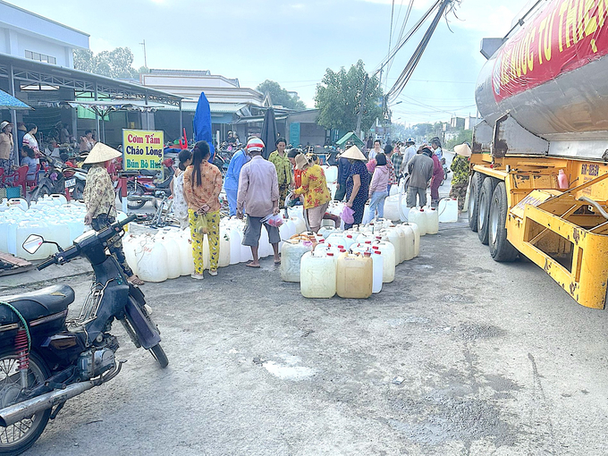 Người dân nhận nước ngọt miễn phí từ xe bồn của Câu lạc bộ bếp ăn từ thiện tại thị xã Gò Công. Ảnh: Minh Đảm.